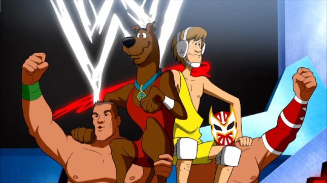 Scooby Doo and Shaggy sit victoriously on the shoulders of WWE superstars John Cena and Sin Cara